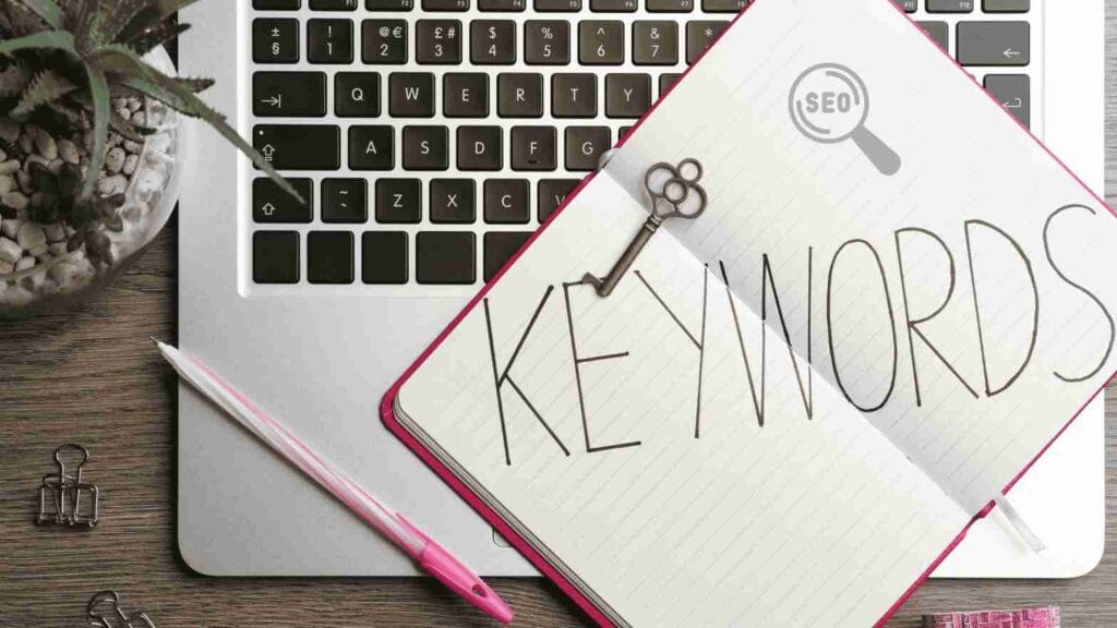 A close-up of a notebook with handwritten SEO keywords related to healthcare, alongside a laptop with a keyword planner tool open.